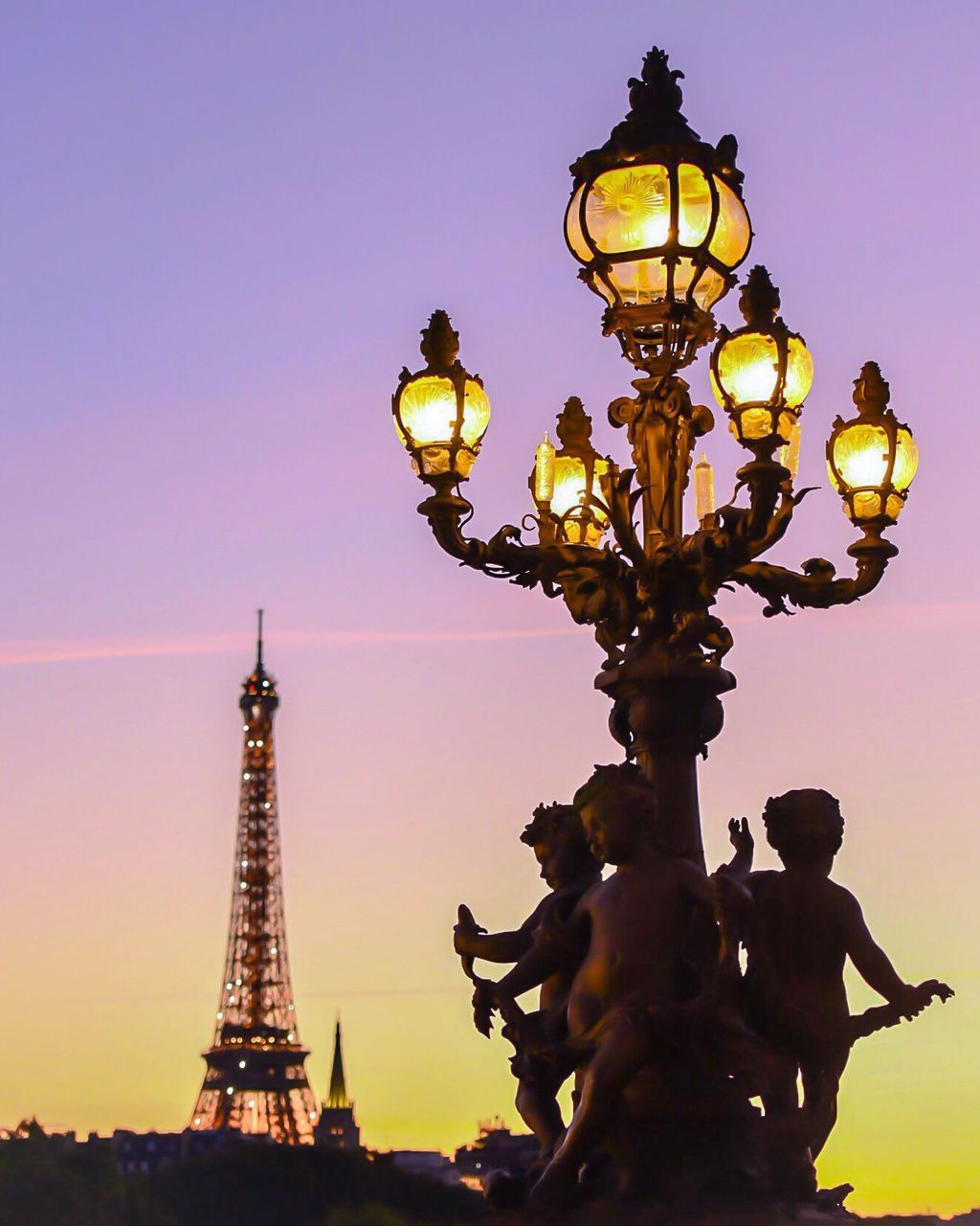 street light, dusk, international landmark, travel destinations, famous place, lighting equipment, tourism, illuminated, capital cities, city, built structure, tall - high, tower, eiffel tower, travel, architecture, sky, culture, cloud, sun, sunbeam, architectural feature, spire, outdoors, lit, skyscraper, city life, majestic