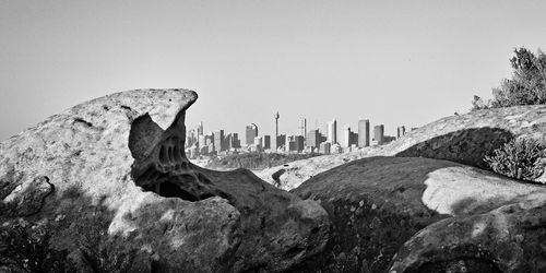 Buildings seen through rocks against clear sky