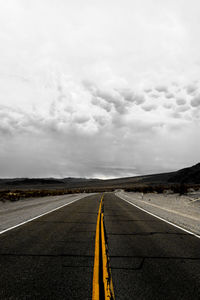 Empty road against cloudy sky