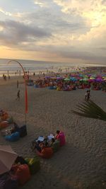 People on beach against sky during sunset