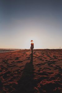 Man standing on beach against sky during sunset