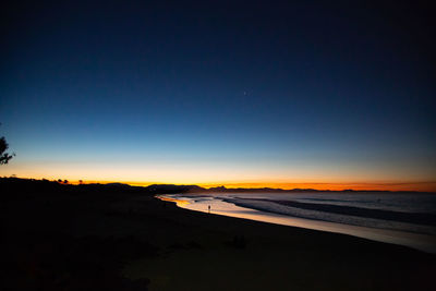 Scenic view of beach against clear sky at sunset