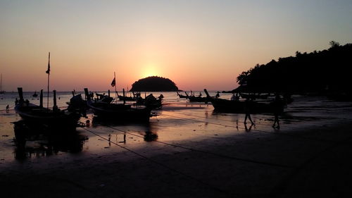 Silhouette boats in marina at sunset