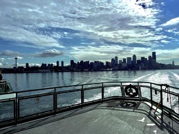 City at waterfront against cloudy sky