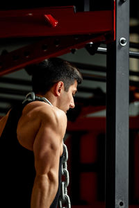 Side view of shirtless man exercising in gym