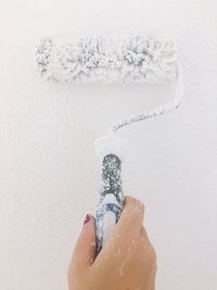 Close-up of woman painting wall with paint roller