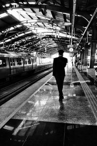 Rear view of man standing on railroad station platform