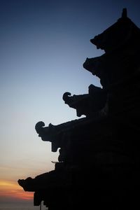 Silhouette statue against sky at sunset