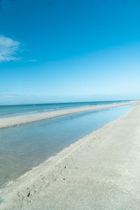 Scenic view of beach against blue sky