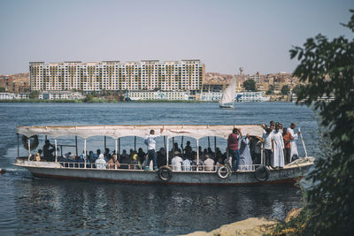 People on river by city against clear sky