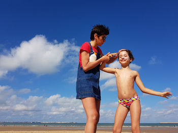 Mother applying sunscreen to daughter at beach