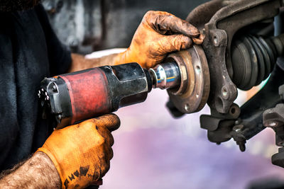 Midsection of mechanic repairing vehicle at repair shop