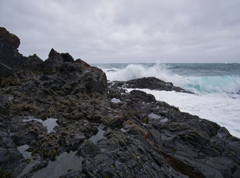 Scenic view of rocks on beach against sky