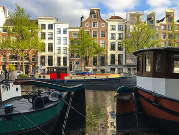 Boats moored in canal amidst buildings in city