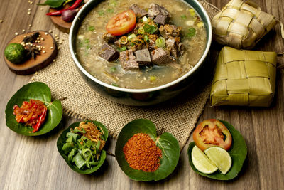 Coto makasar and ketupat, indonesian traditional food, taken with high angle view on table