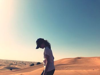 Side view of woman standing on sand dune