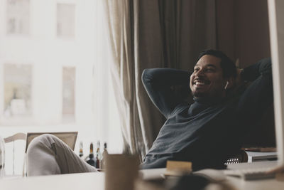 Smiling businessman relaxing while sitting on chair at office