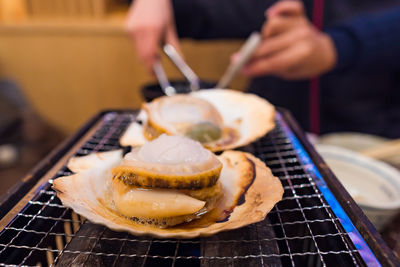 Cropped hands preparing seafood on barbecue grill