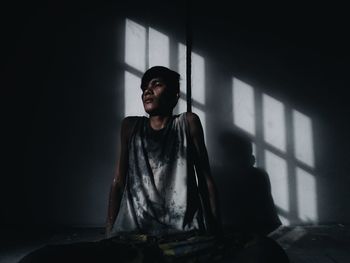 Man sitting in darkroom with sunlight against wall