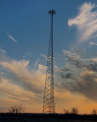 Low angle view of electricity pylon against sky during sunset