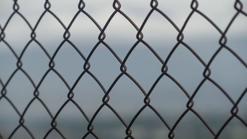 Close-up of chainlink fence against sky