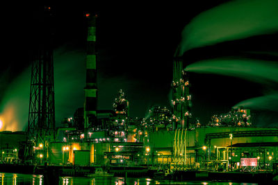 Illuminated factory against sky at night