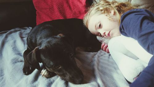 High angle view of girl resting with dog on bed