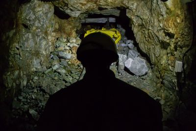 Rear view of silhouette man standing in cave