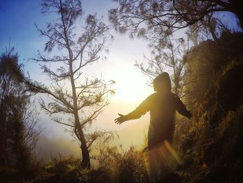 Silhouette hooded person enjoying sunlight during sunrise