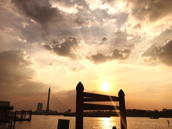 Silhouette bridge over sea against sky during sunset