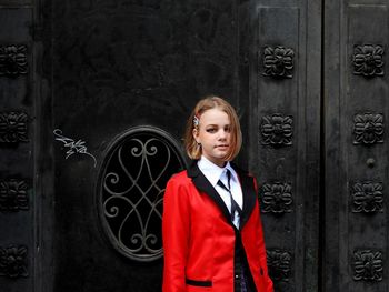 Portrait of young woman standing against door