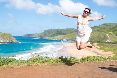 Full length of young woman at beach against sky