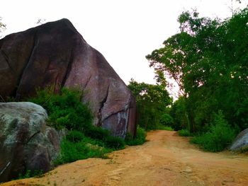 Road amidst rocks and trees against clear sky