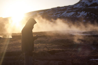 Side view of silhouette man standing against sky during sunset