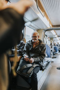 Senior male entrepreneur with mobile phone commuting through bus for work