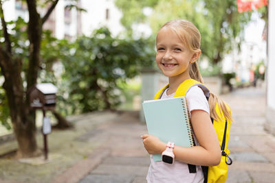 Portrait of smiling boy holding camera while standing outdoors