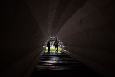 Rear view of silhouette people walking in tunnel