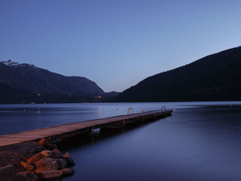 Scenic view of lake against clear blue sky at dusk