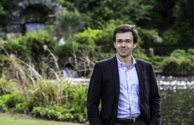 Man in casual suit standing in a countryside setting