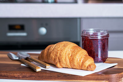 Close-up of breakfast croissant with jam on serving board with cutlery. selective focus.