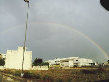 Rainbow over buildings in city against sky