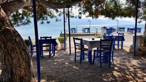 Empty chairs and tables at restaurant by sea