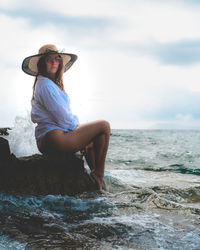 Full length of young woman sitting on beach