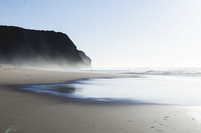 Scenic view of cliff and sea against clear sky