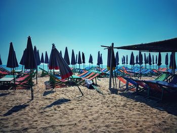 Chairs on beach against clear blue sky