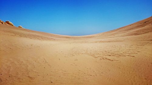 Scenic view of desert against clear blue sky