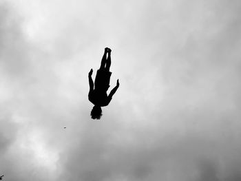 Low angle view of silhouette man jumping against sky