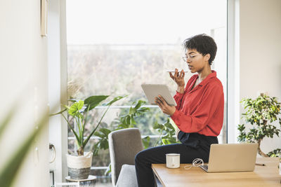 Young woman using mobile phone while sitting on table