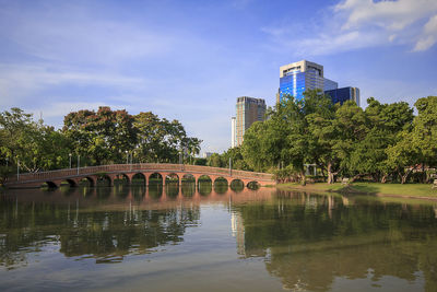 Bridge over river by buildings against sky