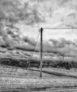 Electricity pylon on field against sky